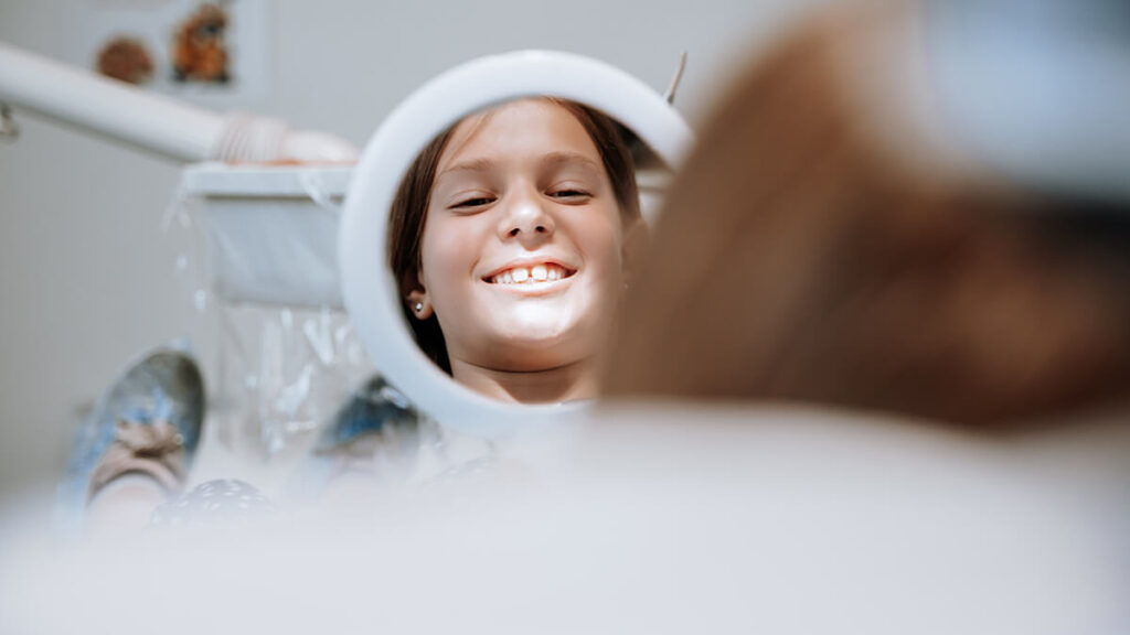 Una giovane paziente che si guarda sorridente allo specchio