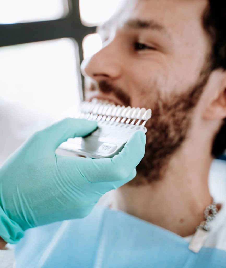 Il dentista mentre nostra al paziente i possibili colori per le faccette estetiche