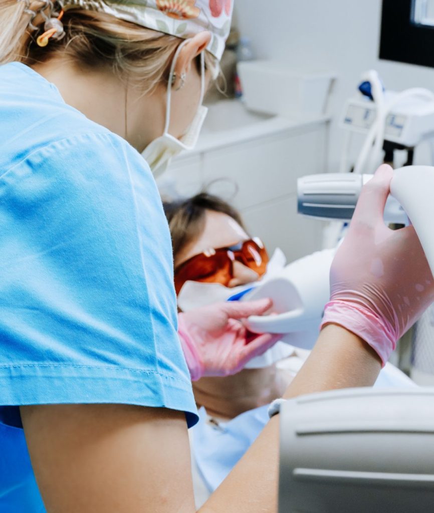 Una paziente si sta sottoponendo alla sbiancamento dentale professionale. Questa è la fase in cui il gel sbiancante attivato da una lampada a raggi UV.