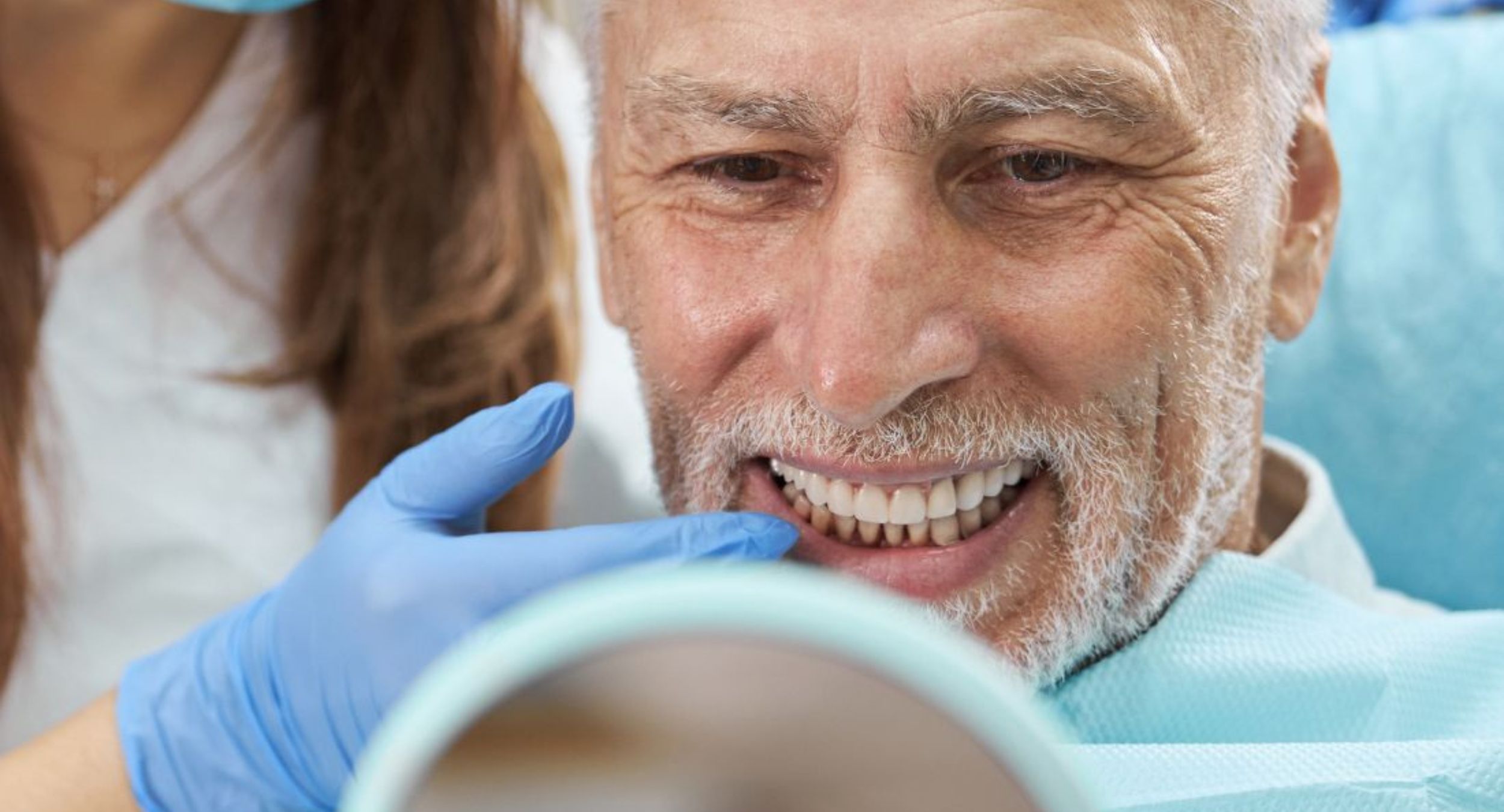 Un signore over 60 che sorride guardandosi allo specchio